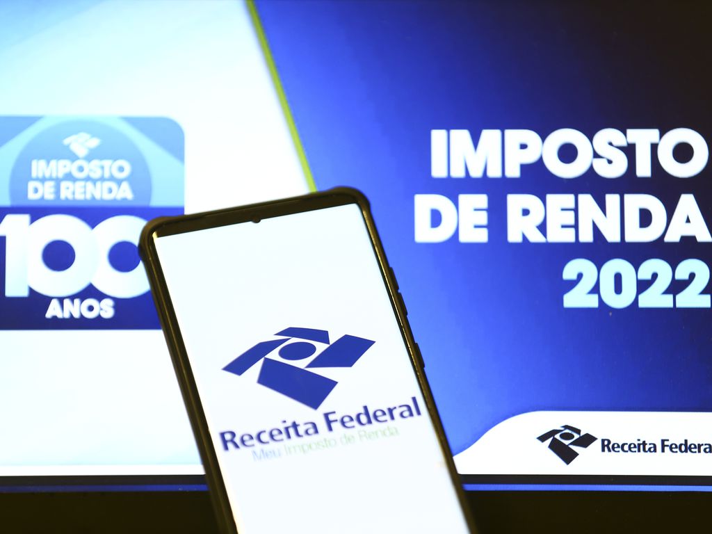aplicativo da receita federal aberto em um smartphone com um letreiro do imposto de renda 2022 ao fundo