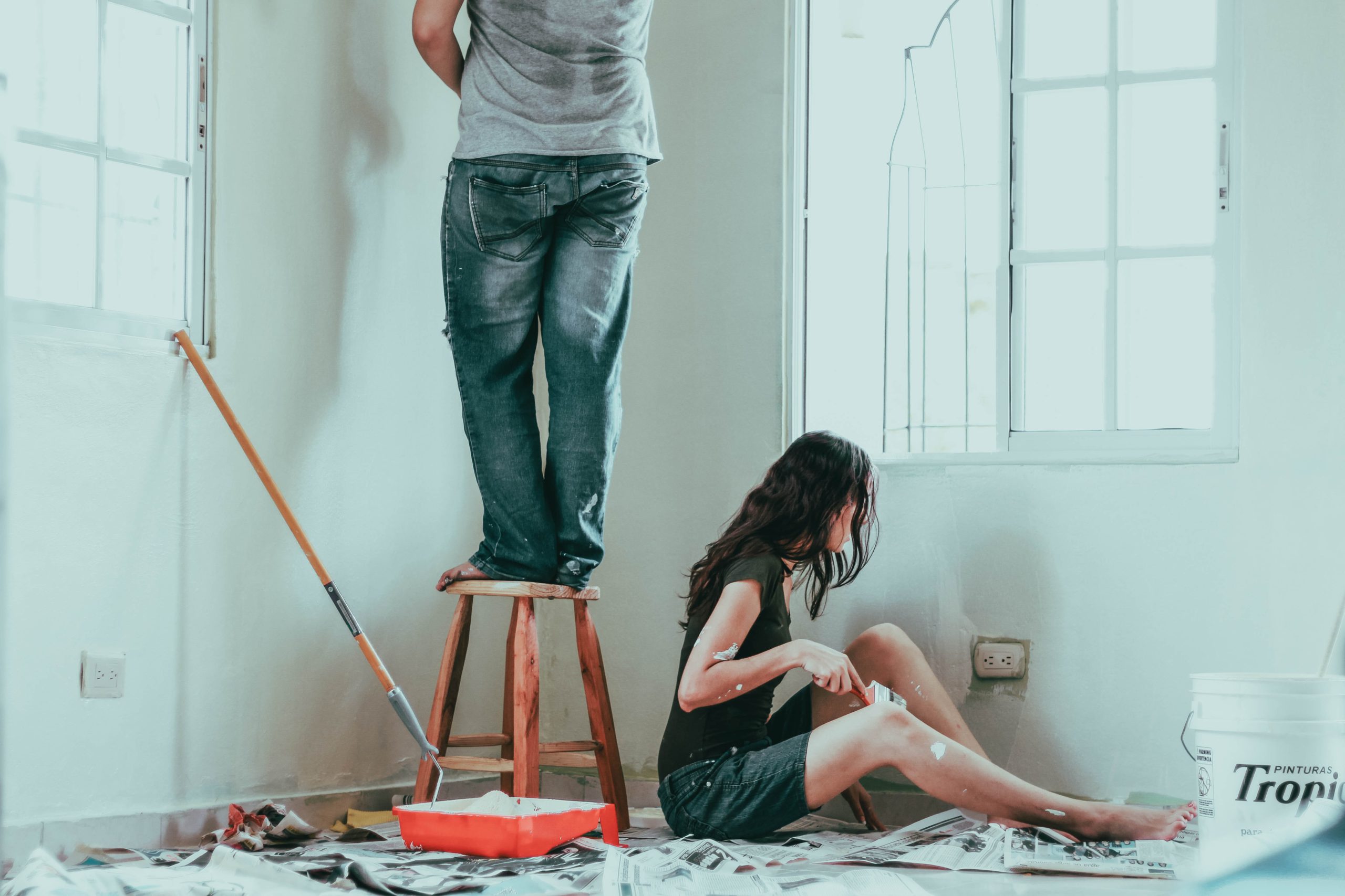 Imagem de duas pessoas pintando as paredes de um apartamento antigo