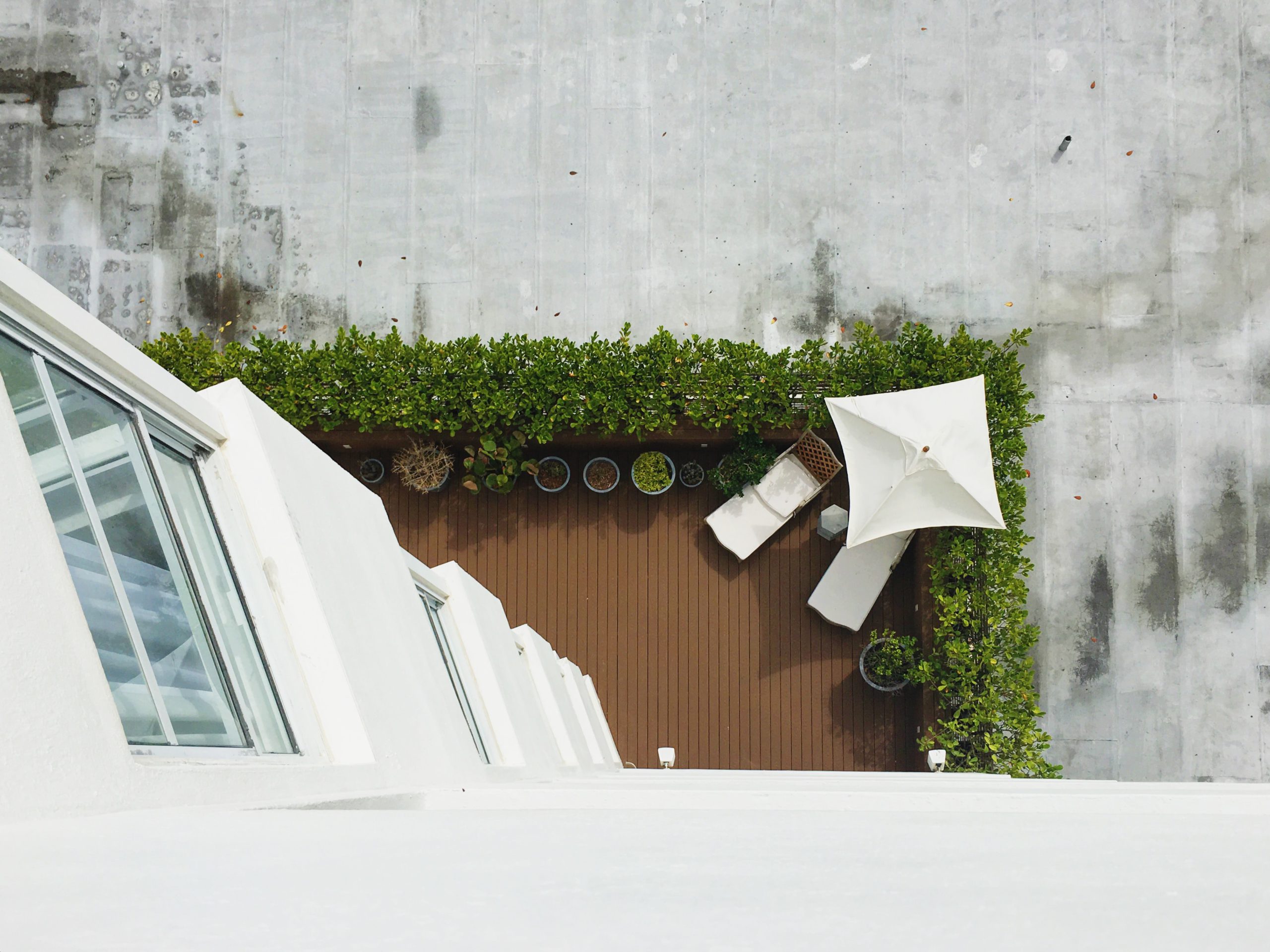 Apartamento garden: varanda vista de cima com guarda-sol, espreguiçadeiras e plantas