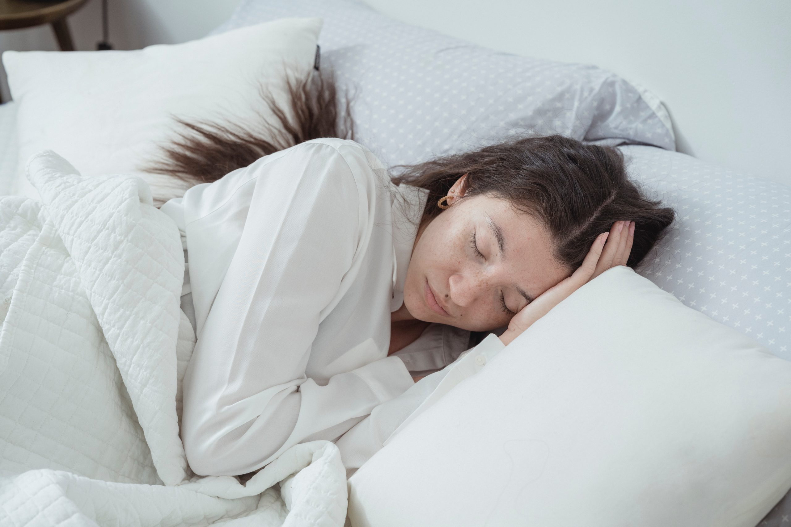 Isolamento acústico: mulher de cabelo preto dormindo em cama com travesseiros brancos